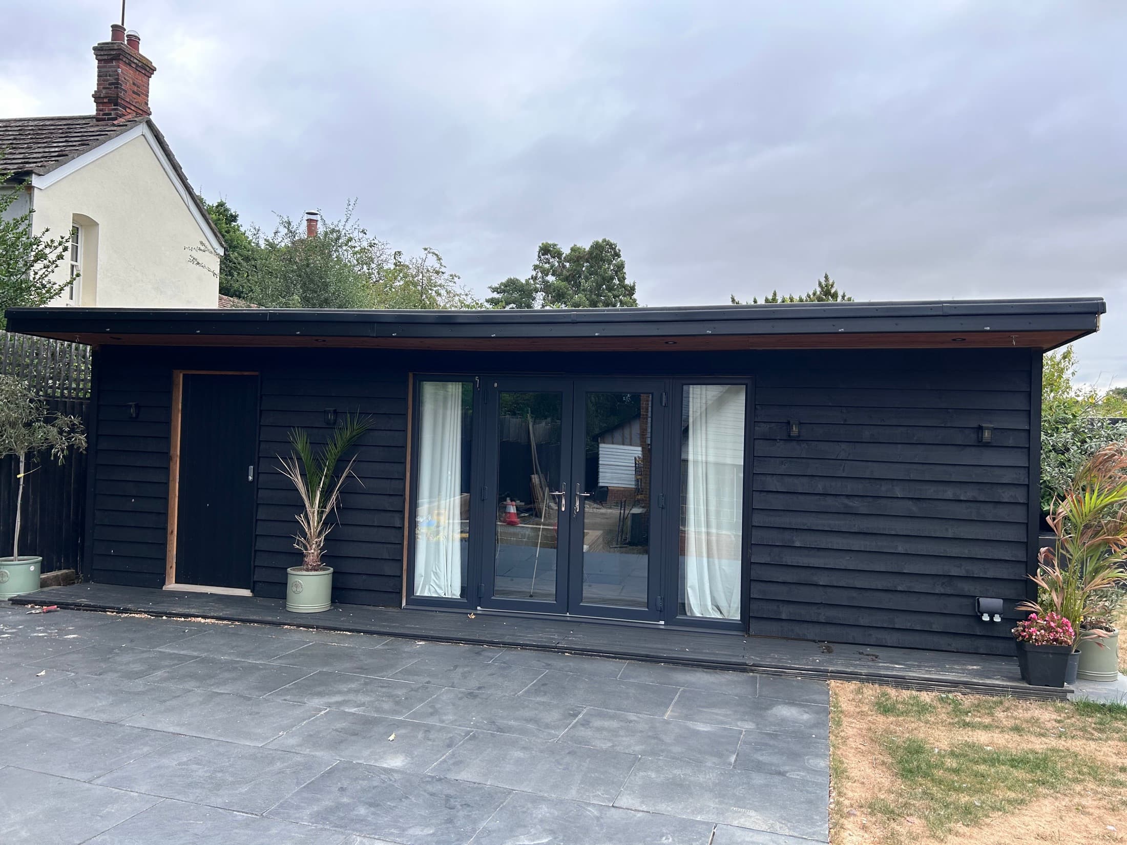 Black timber garden room with patio doors and storage area in Essex